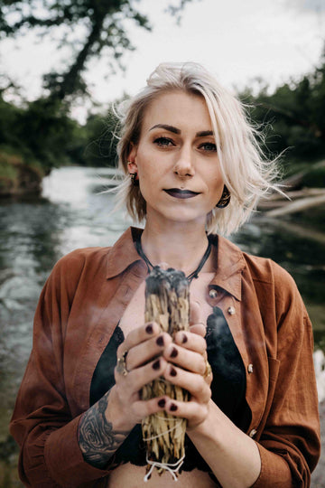 Frau mit Schmuck und Holz in der Hand das raucht